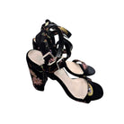Black floral high-heeled shoes on a white background