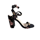 Black high-heeled sandal with floral embroidery on a white background