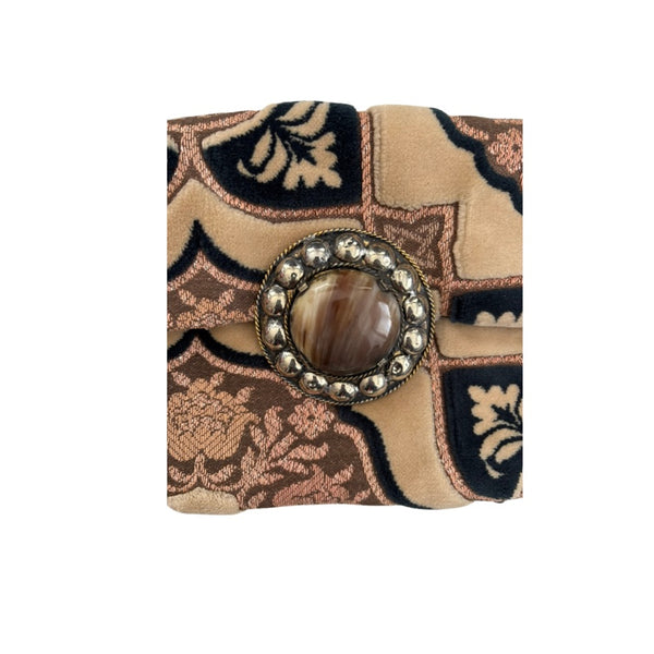 Decorative clutch with intricate patterns and a central button on a white background