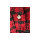 Red and black checkered fabric with a button on a white background