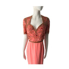 Coral dress with intricate gold embroidery on a mannequin against a white background