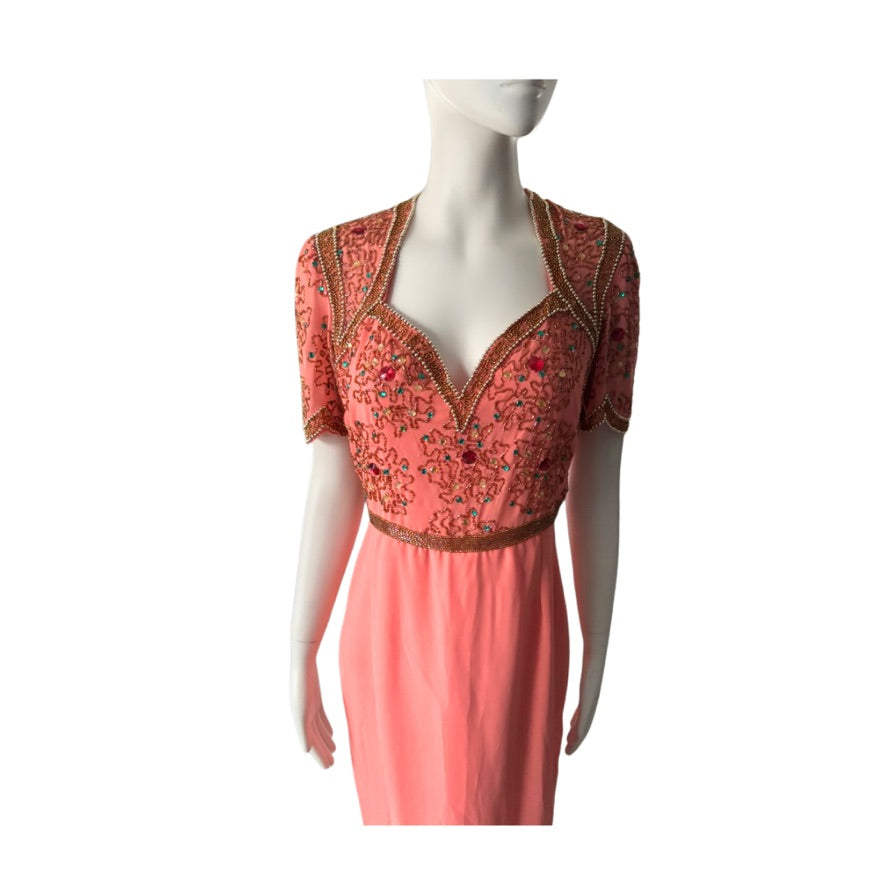 Coral dress with intricate gold embroidery on a mannequin against a white background