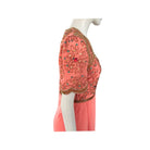 Coral dress with intricate beadwork on a mannequin against a white background