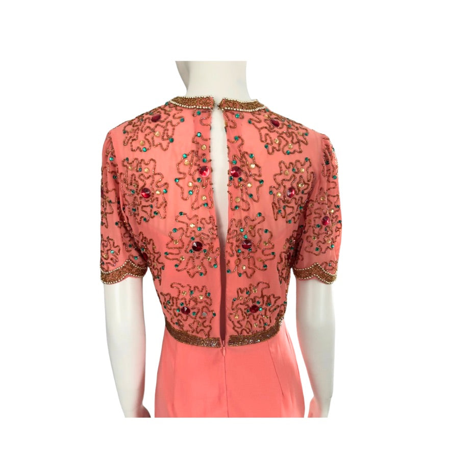 Peach-colored dress with intricate beadwork on a mannequin against a white background