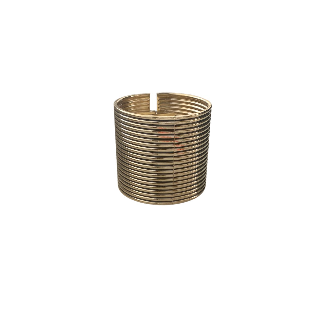 A gold cuff bracelet with a corrugated design and hinge fastening.
