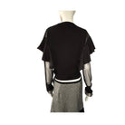 Mannequin wearing a black top with sheer sleeves and a patterned skirt on a white background