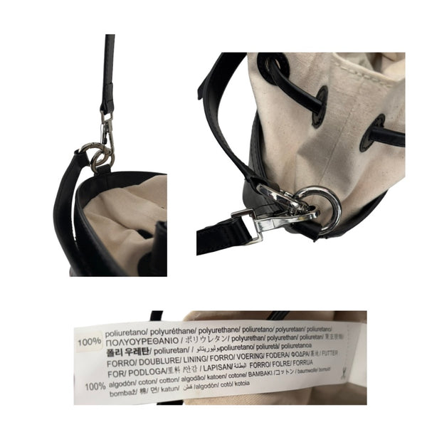 Close-up of a beige bag with black strap and metal clasp, featuring a label with text.