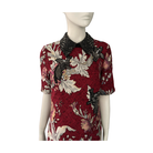 Red floral dress with black embellished details on a mannequin against a white background