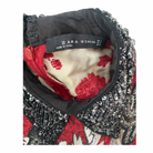 Close-up of a Zara Woman label on an embroidered garment with red and black patterns.