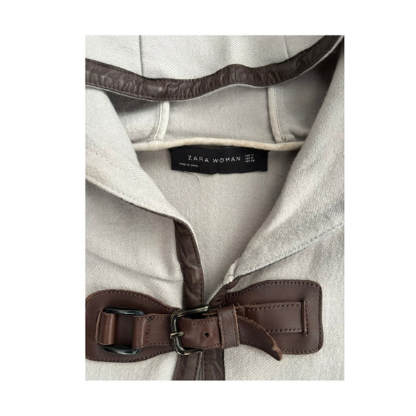 Close-up of a Zara Woman coat with a brown belt and visible label.
