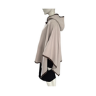 Mannequin wearing a beige cape with black trim on a white background