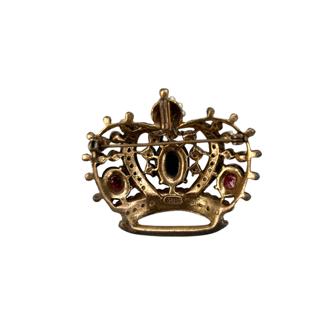 Gold crown-shaped brooch with red gemstones on a white background